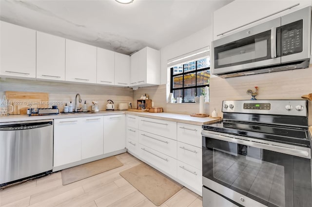 1339 14th Ter, Miami Beach, FL 33139 - kitchen featuring appliances with stainless steel finishes, light countertops, decorative backsplash, and white cabinetry
