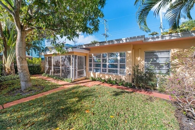 101 Lucerne Ave, Lake Worth, FL 33460 - back of property with a sunroom, a lawn, and stucco siding