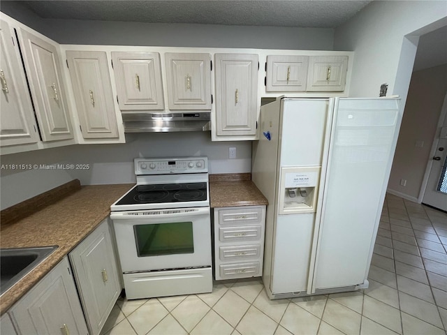413 Saxony I Unit 413, Delray Beach, FL 33446 - kitchen featuring white appliances, under cabinet range hood, light tile patterned floors, dark countertops, and white cabinets