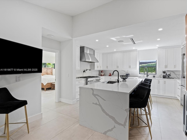 4531 SW 15th St, Miami, FL 33134 - kitchen featuring wall chimney exhaust hood, backsplash, white cabinetry, a center island with sink, and light tile patterned floors
