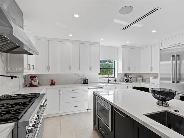 4531 SW 15th St, Miami, FL 33134 - kitchen with high quality appliances, wall chimney exhaust hood, light tile patterned floors, light stone counters, and white cabinetry