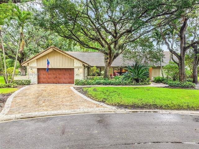 10123 Vestal Ct, Coral Springs, FL 33071 - mid-century modern home with an attached garage, driveway, stone siding, a tiled roof, and a front yard