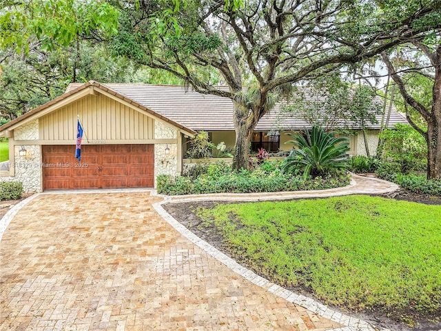 10123 Vestal Ct, Coral Springs, FL 33071 - view of front of house with a tile roof, an attached garage, stone siding, driveway, and board and batten siding