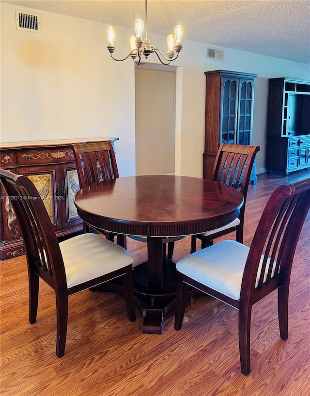 2304 Lucaya Ln Unit J1, Coconut Creek, FL 33066 - dining space featuring a chandelier, wood finished floors, and a textured ceiling