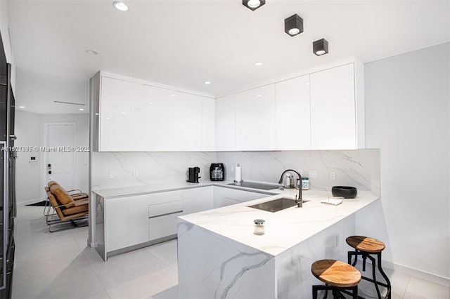 10857 NW 84th St, Doral, FL 33178 - kitchen with modern cabinets, a peninsula, light stone counters, white cabinetry, and light tile patterned floors