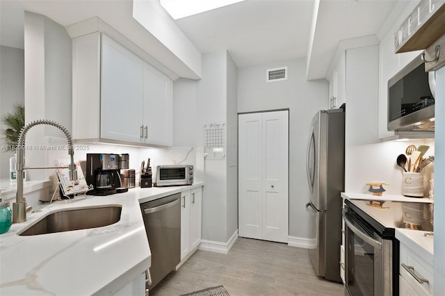 888 Brickell Key Dr Unit 1006, Miami, FL 33131 - kitchen with appliances with stainless steel finishes, light wood-style flooring, and white cabinetry