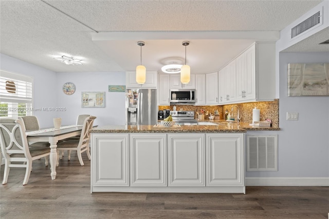 3021 Ellesmere B 3021, Deerfield Beach, FL 33442 - kitchen featuring appliances with stainless steel finishes, dark stone countertops, a textured ceiling, white cabinetry, and a peninsula