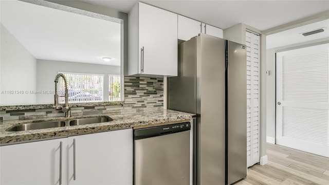 17901 NW 68th Ave Unit Q102, Hialeah, FL 33015 - kitchen featuring appliances with stainless steel finishes, light stone counters, white cabinets, light wood finished floors, and tasteful backsplash