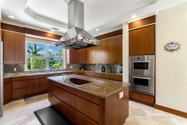 180 Solano Prado, Coral Gables, FL 33156 - kitchen featuring appliances with stainless steel finishes, island exhaust hood, a kitchen island, decorative backsplash, and brown cabinetry