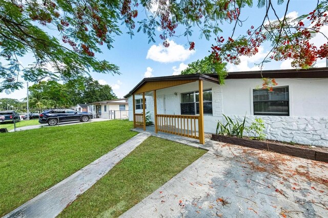 5736 Simms St, Hollywood, FL 33021 - view of front of house featuring a front yard, a porch, stucco siding, and stone siding