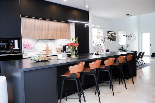 2836 W Trade Ave Unit 2836, Miami, FL 33133 - kitchen with dark countertops, modern cabinets, backsplash, a breakfast bar, and a large island