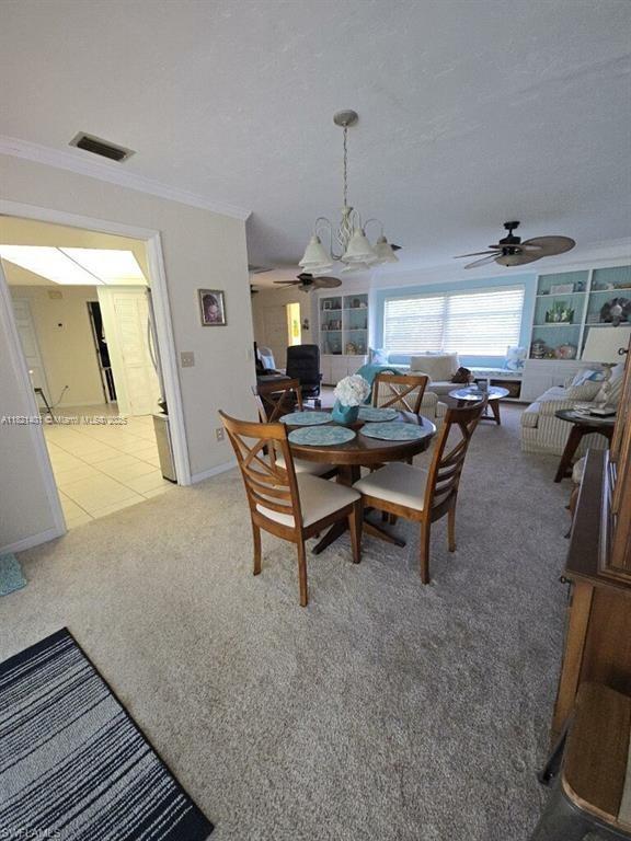 13001 Shetland Ln, Fort Myers, FL 33912 - dining area featuring ceiling fan, crown molding, and light colored carpet