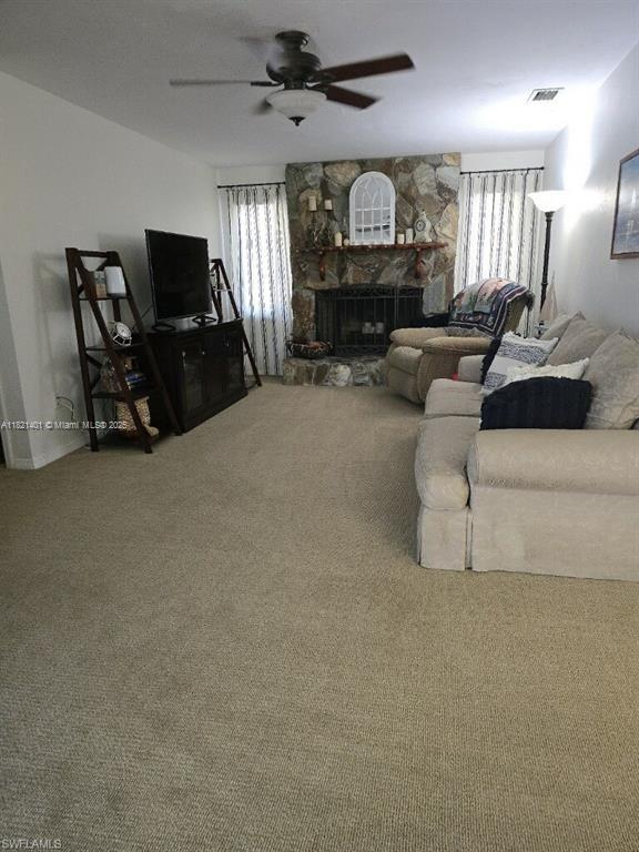 13001 Shetland Ln, Fort Myers, FL 33912 - carpeted living room with ceiling fan, plenty of natural light, and a fireplace