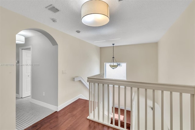 15631 SW 53rd St, Miramar, FL 33027 - hallway featuring arched walkways, wood finished floors, a textured ceiling, and an upstairs landing