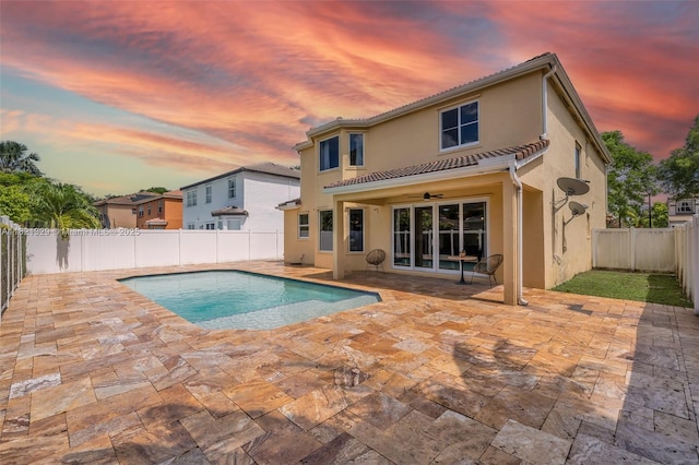 15631 SW 53rd St, Miramar, FL 33027 - back of property at dusk with a patio, a fenced backyard, stucco siding, a ceiling fan, and a tile roof