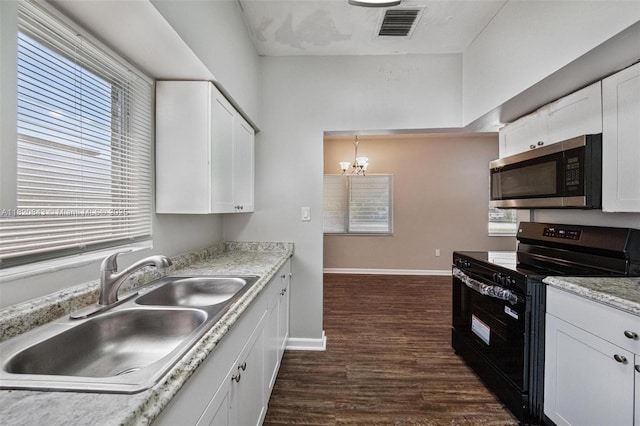 6428 Plunkett St, Hollywood, FL 33023 - kitchen featuring black range oven, stainless steel microwave, a chandelier, dark wood-style floors, and white cabinetry