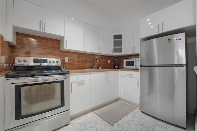 1200 Euclid Ave Unit 103, Miami Beach, FL 33139 - kitchen with appliances with stainless steel finishes, white cabinets, tasteful backsplash, light countertops, and dark speckled floor