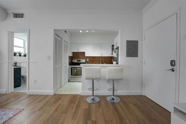 1200 Euclid Ave Unit 103, Miami Beach, FL 33139 - kitchen featuring stainless steel appliances, electric panel, light wood-style floors, white cabinets, and ornamental molding