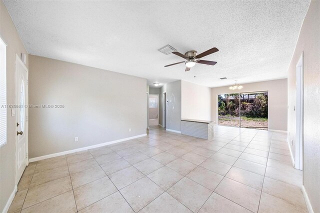 6442 Oak St, Hollywood, FL 33024 - empty room with a textured ceiling, ceiling fan, light tile patterned floors, and a chandelier