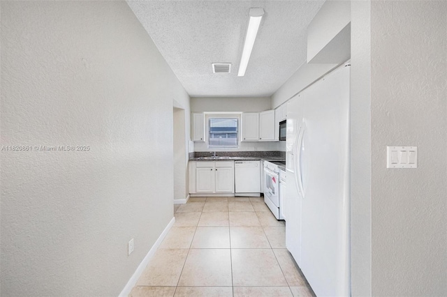 6442 Oak St, Hollywood, FL 33024 - kitchen featuring white appliances, a textured ceiling, white cabinets, a textured wall, and dark countertops