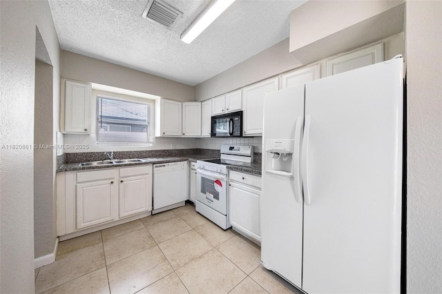 6442 Oak St, Hollywood, FL 33024 - kitchen with white appliances, dark countertops, white cabinets, light tile patterned floors, and a textured ceiling