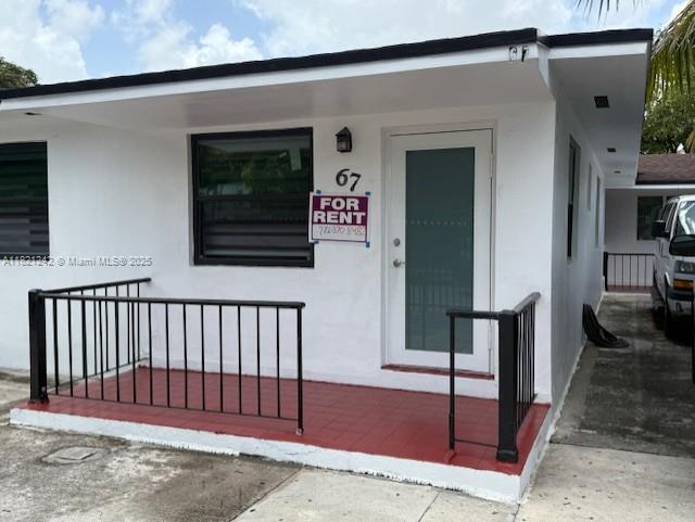 67 NW 34th St, Miami, FL 33127 - doorway to property featuring stucco siding and a porch