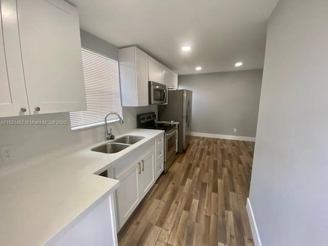 345 NE 168th St, North Miami Beach, FL 33162 - kitchen featuring appliances with stainless steel finishes, white cabinets, light wood-style flooring, light countertops, and recessed lighting