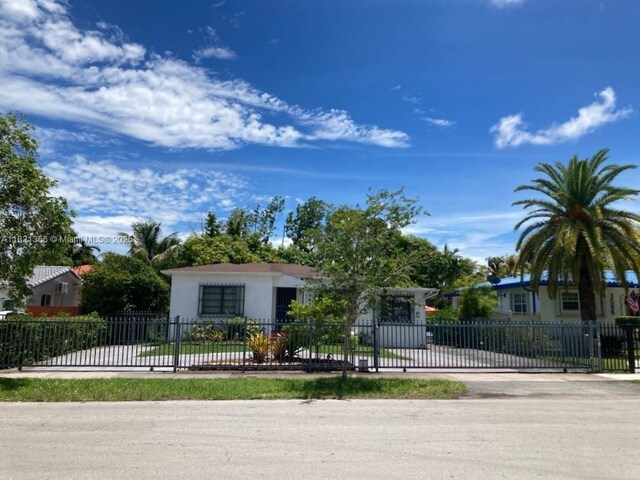 3082 NW 4th St, Miami, FL 33125 - obstructed view of property with stucco siding, a fenced front yard, concrete driveway, and a gate