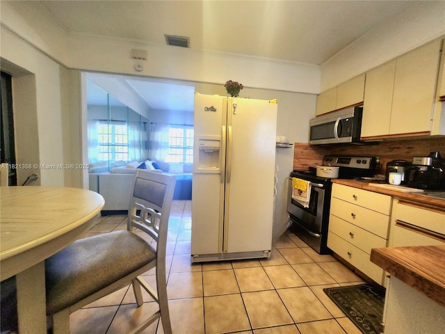 3082 NW 4th St, Miami, FL 33125 - kitchen with appliances with stainless steel finishes, crown molding, light tile patterned flooring, tasteful backsplash, and cream cabinetry