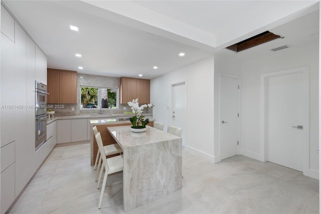 5211 Granada Blvd, Coral Gables, FL 33146 - kitchen with modern cabinets, recessed lighting, decorative backsplash, a kitchen island, and double oven