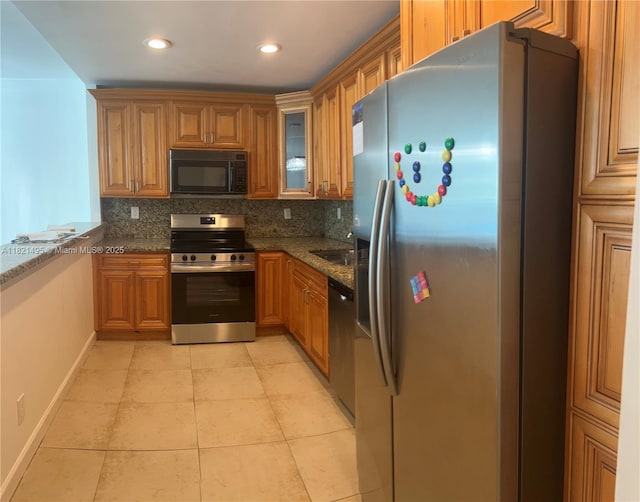 19390 Collins Ave Unit 207, Sunny Isles Beach, FL 33160 - kitchen with stainless steel appliances, brown cabinetry, tasteful backsplash, dark stone countertops, and light tile patterned floors
