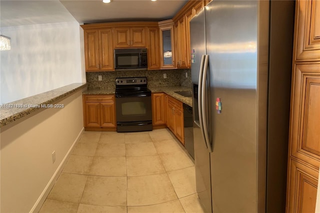 19390 Collins Ave Unit 207, Sunny Isles Beach, FL 33160 - kitchen featuring black appliances, brown cabinets, light tile patterned flooring, dark stone countertops, and decorative backsplash