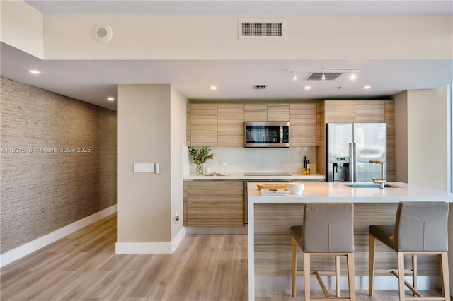 185 SW 7th St Unit 803, Miami, FL 33130 - kitchen featuring stainless steel appliances, modern cabinets, light countertops, light wood finished floors, and a breakfast bar