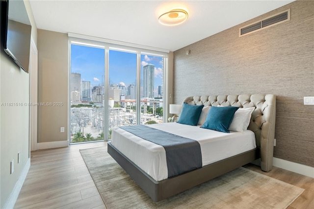 185 SW 7th St Unit 803, Miami, FL 33130 - bedroom with a wall of windows, a view of skyline, light wood-type flooring, and an accent wall