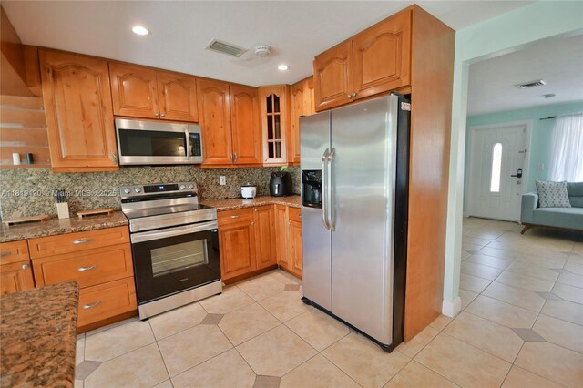 5815 S Farragut Dr, Hollywood, FL 33021 - kitchen featuring appliances with stainless steel finishes, stone countertops, backsplash, glass insert cabinets, and light tile patterned floors