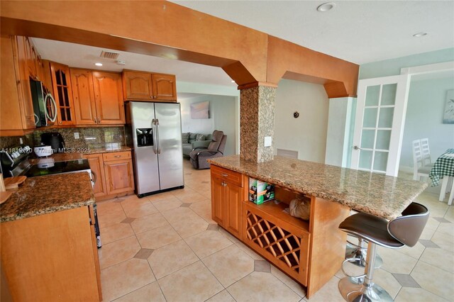 5815 S Farragut Dr, Hollywood, FL 33021 - kitchen featuring stainless steel appliances, dark stone countertops, brown cabinetry, glass insert cabinets, and backsplash