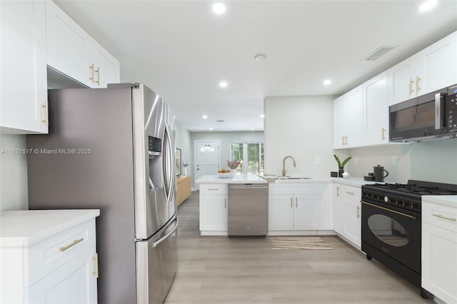 4521 SW 25th Ter, Dania Beach, FL 33312 - kitchen with appliances with stainless steel finishes, a peninsula, recessed lighting, white cabinets, and light wood-type flooring