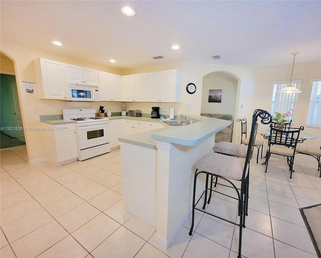 357 Moscato Dr, Davenport, FL 33897 - kitchen with white appliances, a breakfast bar, white cabinets, light countertops, and recessed lighting