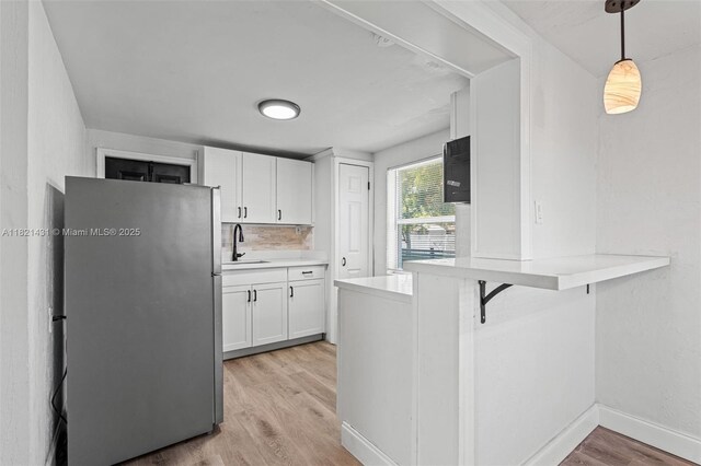 1001 NW 4th Ave, Pompano Beach, FL 33060 - kitchen with freestanding refrigerator, white cabinetry, light wood-style floors, light countertops, and a peninsula