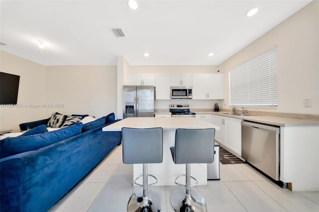 2699 SE 19th St, Homestead, FL 33035 - kitchen featuring stainless steel appliances, a breakfast bar, open floor plan, a kitchen island, and white cabinetry