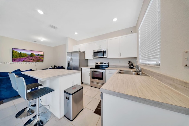 2699 SE 19th St, Homestead, FL 33035 - kitchen featuring stainless steel appliances, a breakfast bar area, light countertops, white cabinetry, and light tile patterned floors