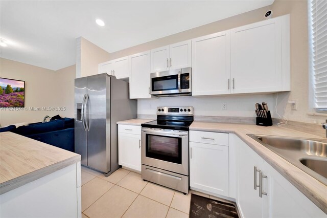 2699 SE 19th St, Homestead, FL 33035 - kitchen with stainless steel appliances, light tile patterned flooring, white cabinets, light countertops, and open floor plan