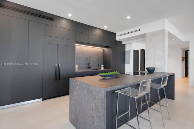 11 Island Ave Unit Ph2, Miami Beach, FL 33139 - kitchen with a breakfast bar, modern cabinets, dark countertops, a center island, and light tile patterned floors