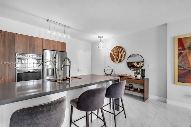 325 S Biscayne Blvd Unit 2515, Miami, FL 33131 - kitchen featuring appliances with stainless steel finishes, light marble finish floors, dark countertops, a breakfast bar area, and brown cabinetry