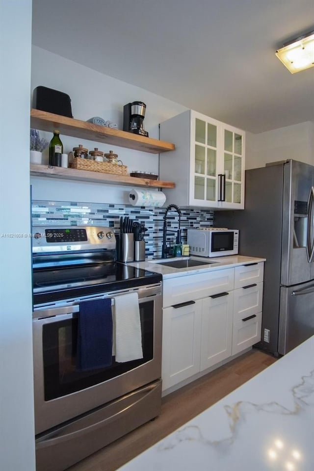7904 W Dr Unit 501, North Bay Village, FL 33141 - kitchen featuring stainless steel appliances, wood finished floors, white cabinets, tasteful backsplash, and open shelves