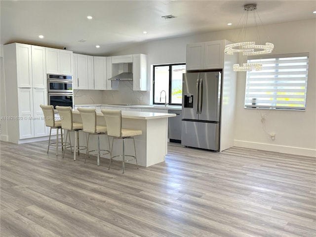 240 SW 55th Ave, Miami, FL 33134 - kitchen featuring stainless steel appliances, wall chimney exhaust hood, a center island, light wood finished floors, and recessed lighting