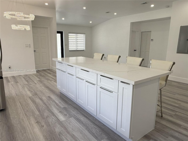 240 SW 55th Ave, Miami, FL 33134 - kitchen featuring electric panel, light wood finished floors, a kitchen island, a kitchen bar, and white cabinetry