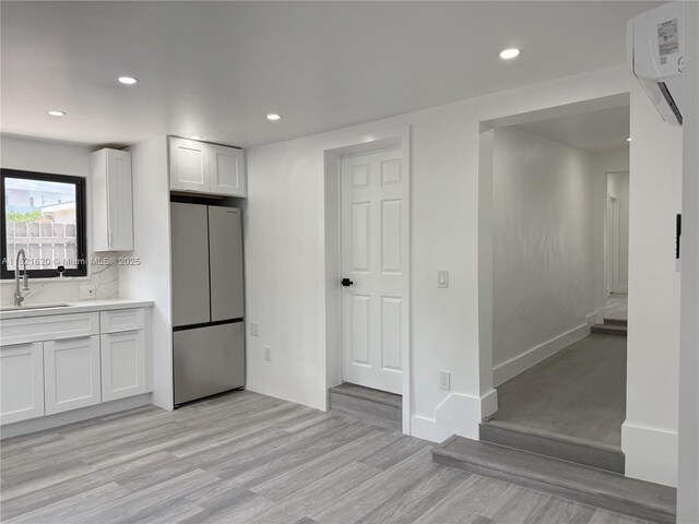 240 SW 55th Ave, Miami, FL 33134 - kitchen featuring a wall mounted air conditioner, freestanding refrigerator, light wood-type flooring, white cabinets, and light countertops