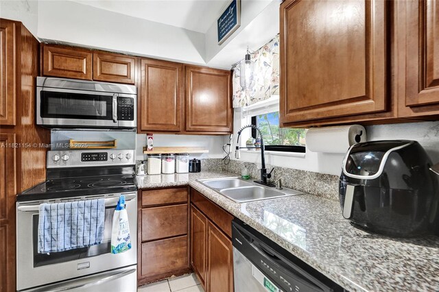2041 Arcadia Dr, Miramar, FL 33023 - kitchen with appliances with stainless steel finishes, brown cabinetry, light tile patterned flooring, and light countertops