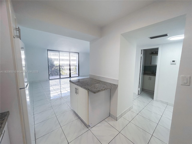 1800 Collins Ave Unit 5C, Miami Beach, FL 33139 - kitchen featuring light tile patterned floors, white cabinetry, stone counters, and freestanding refrigerator